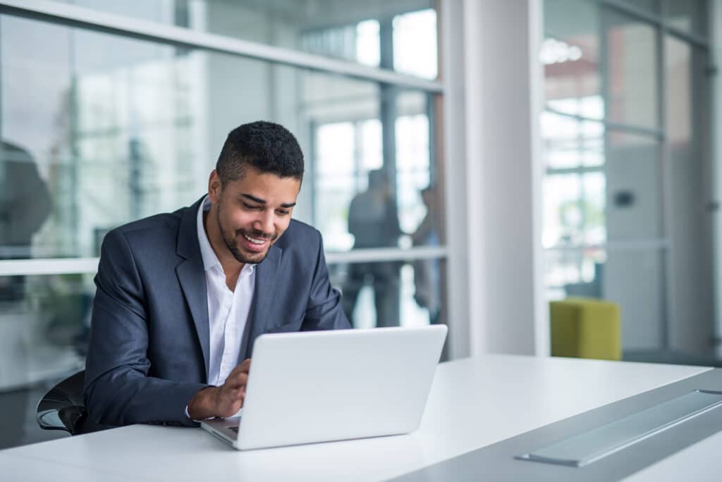 IT technician in business suit smiles while working at a laptop in an IT services company office