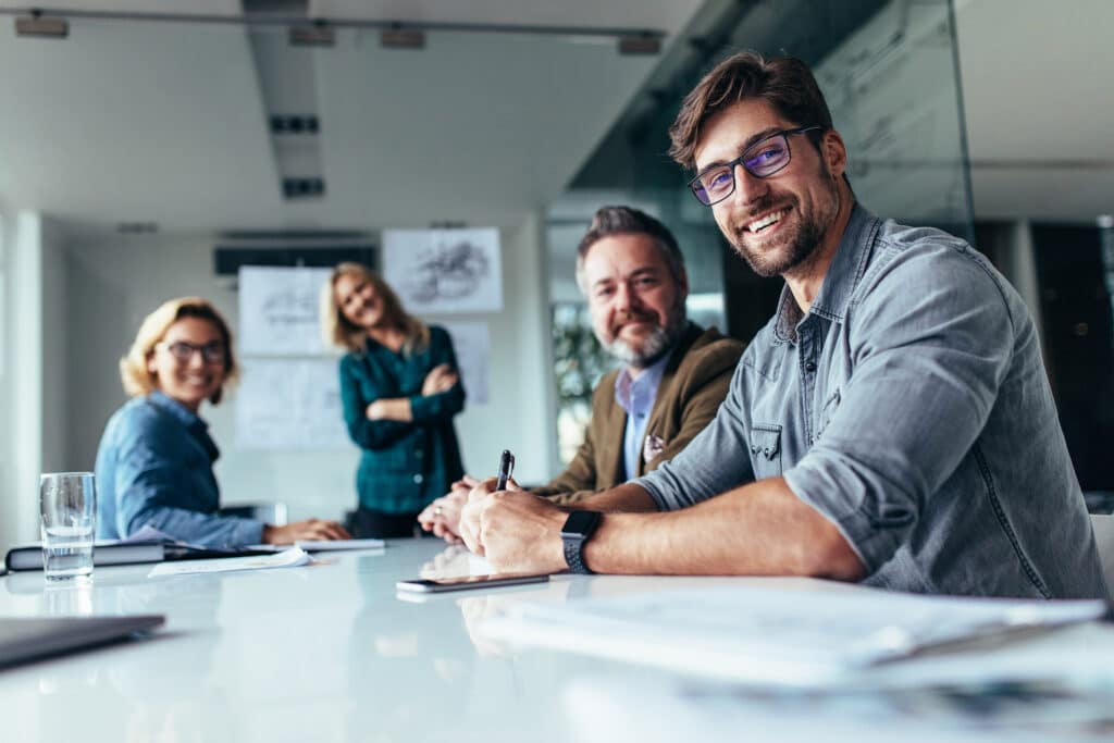 IT business team looks at camera from down a table