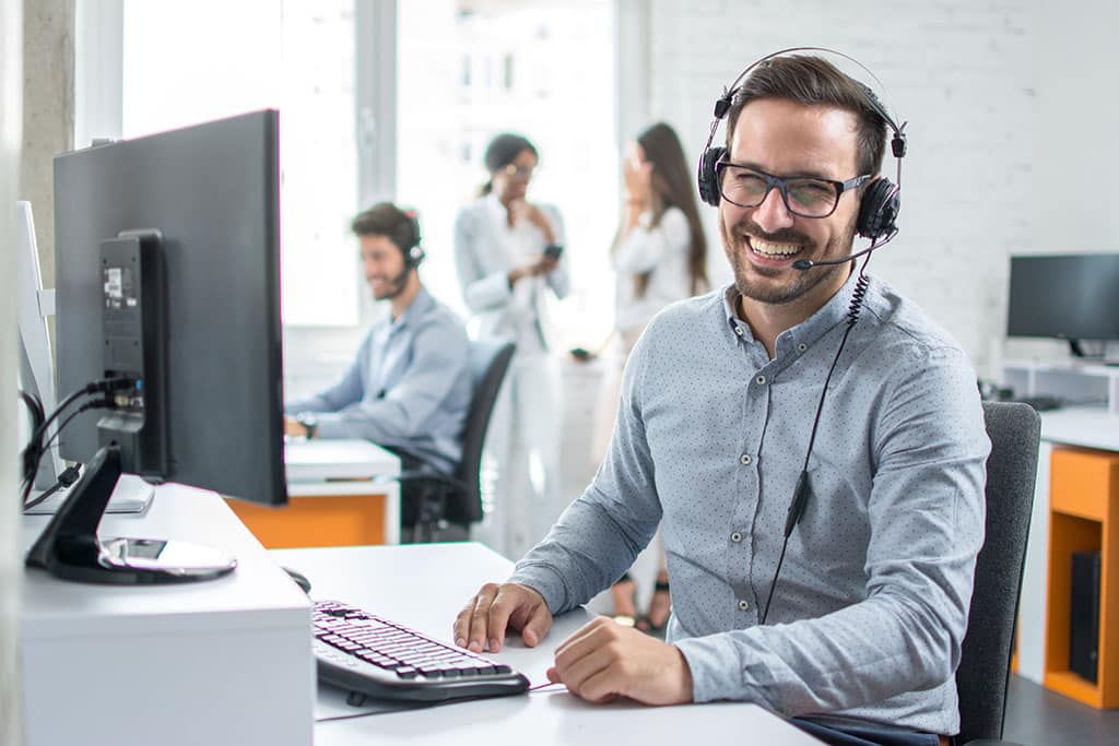 Happy young male customer support executive working in office at a Stamford IT services company